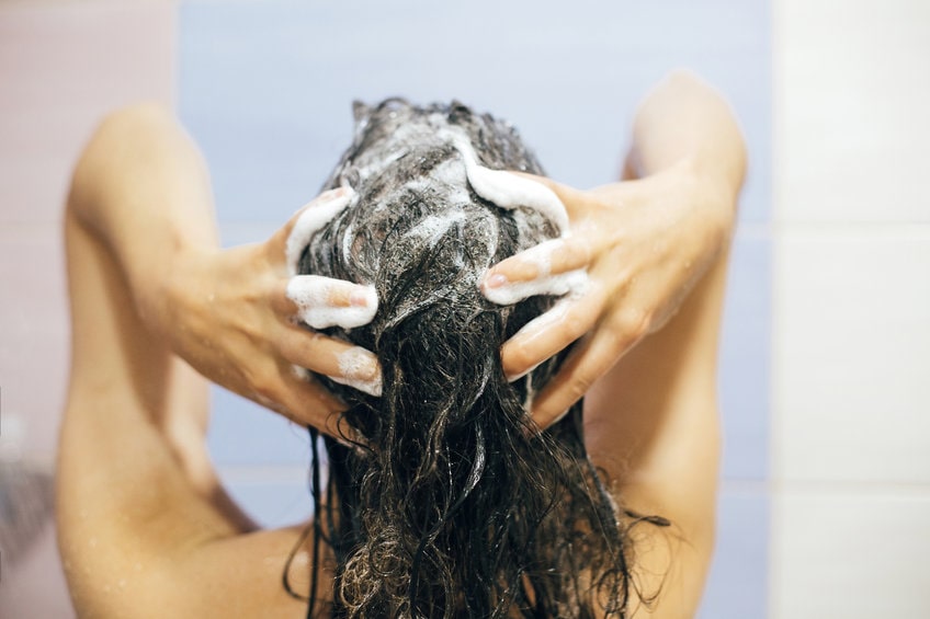 femme se lavant les cheveux avec du shampoing solide